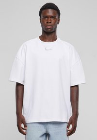 Balta didelė t-shirt marškinėliai su trumpomis rankovėmis, apvaliu kaklu ir siuvinėtu logotipu krūtinėje. Pagaminta iš minkštos medvilnės su lygiu paviršiumi.
