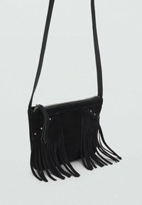 Borsa a tracolla in suede nero con chiusura a zip, caratterizzata da lunghe frange decorative e borchie metalliche sulla parte anteriore. Tracolla regolabile.