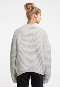 Grau gestrickter Pullover mit einem strukturierten Muster, weiten Ärmeln und lockerer Passform. Der Saum ist gerippt und verstärkt das gemütliche Erscheinungsbild.