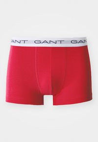 Rote Boxershorts aus weichem Material, mit einem weißen elastischen Bund und dem navyblauen "GANT"-Logo. Glatte Textur und enganpassendes Design.