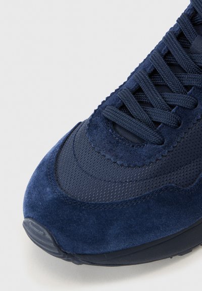 Baskets bleu marine avec une tige en suède texturé et en mesh. Caractéristiques : bout rond, lacets plats et semelle en caoutchouc lisse.