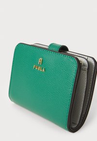 Portafoglio in pelle teal con superficie texturizzata, logo "FURLA" dorato e interno grigio a contrasto. Presenta una chiusura a soffietto sicura e un design compatto.