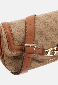 Bruine handtas met een patroon, gemaakt van gestructureerde stof met gladde leren accenten. Voorzien van een lange schouderriem en een gouden hardware gespsluiting.