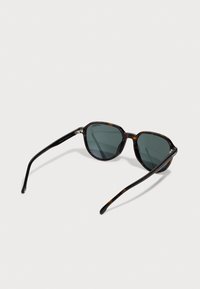 Sunglasses z želvovinovým vzorem s tmavě šedými skly, kulatými rámy z polykarbonátu a štíhlými černými stranicemi. Výrazný tvar s geometrickými akcenty.