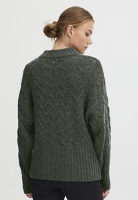 Dunkelgrüner Strickpullover mit Zopfmuster, geripptem Saum und rundem Halsausschnitt. Das Material wirkt weich und strukturiert.