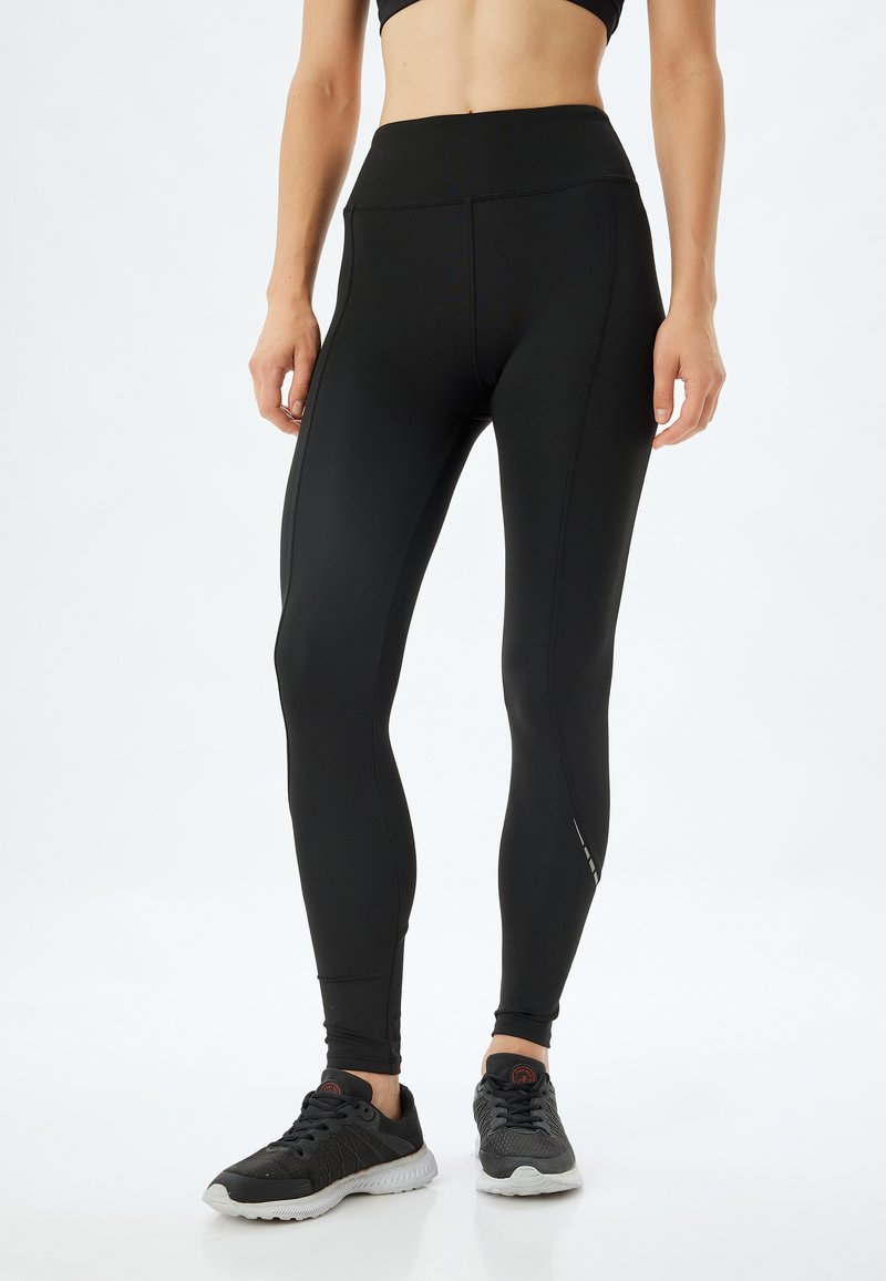 Zwarte legging gemaakt van rekbare stof, high-waisted met vlakke naden, met een slank, aansluitend ontwerp en een subtiele logo bij de enkel.