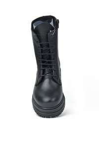 Botín de cuero negro hasta el tobillo con puntera redondeada, diseño de cordones en la parte delantera y suela de goma. Presenta un zipper lateral y textura suave.