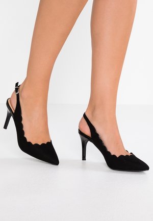 Talons slingback en suede noir avec un bout pointu, des bords festonnés et un fin talon aiguille noir. Décoré d'une boucle métallique.