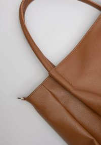 Borsa tote in pelle marrone con finitura morbida e texturizzata, dotata di una tracolla e chiusura con zip. Design semplice senza ulteriori motivi o accenti.