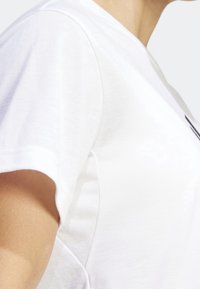 Camiseta blanca de manga corta con cuello redondo, confeccionada con un tejido ligero y suave, y detalles de costuras sutiles en el hombro.