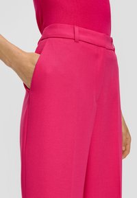 Fuchsia wijde broek met een gladde textuur, een op maat gemaakte tailleband en zijzakken. De stof lijkt lichtgewicht en gestructureerd.