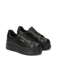 Baskets en cuir noires avec une semelle épaisse, dotées d'œillets dorés et de lacets assortis, avec le logo de la marque embossé sur le côté.