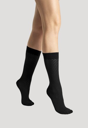 Knæ-høje sorte sokker med et tekstureret, ribbet design og en kontrasterende sort bånd foroven. Glat overflade med skråstribet mønster.