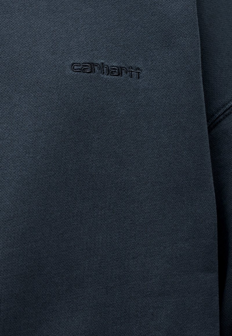 Felpa grigia scura in tessuto strutturato con scollo rotondo. Presenta un logo "Carhartt" in rilievo discreto sul petto.