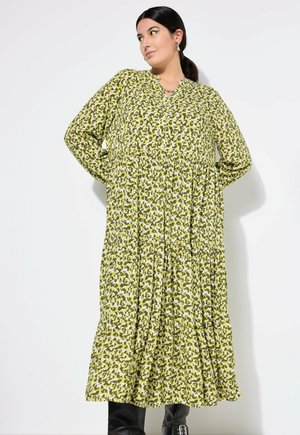 Grønne trykte maxikjole med V-udskæring, lange ærmer, knapper og lagdelt kant. Stoffet har et bladlignende mønster i nuancer af grønt.