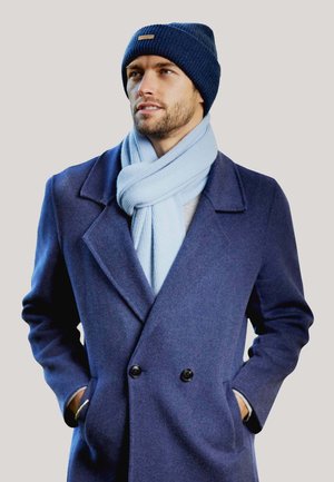Cappotto in lana blu navy con chiusura doppiopetto, sciarpa azzurro chiaro a coste e berretto coordinato. Tessuto liscio, design minimalista.