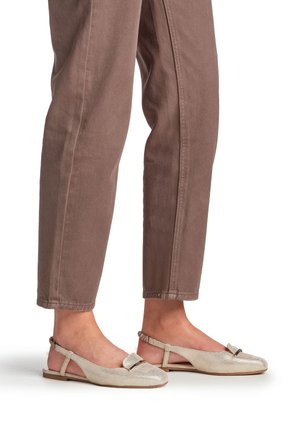 Metallic beige slingback flats with a mesh texture, bow accent, and open sides. Paired with light brown tapered pants.