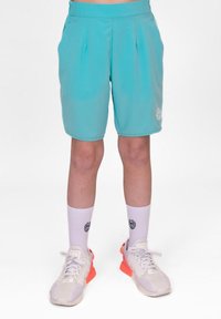 Pantalones cortos deportivos turquesa con pliegues laterales, cintura elástica y detalle de logo. Combinados con calcetines blancos y zapatillas con detalles en naranja.