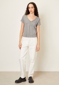 Pilkas trumpomis rankovėmis V formos kaklo marškinėliai laisvu siluetu, derinami su baltais džinsiniais kelnėmis aukštu liemeniu ir juodomis klumpėmis. Paprastas, švarus dizainas.