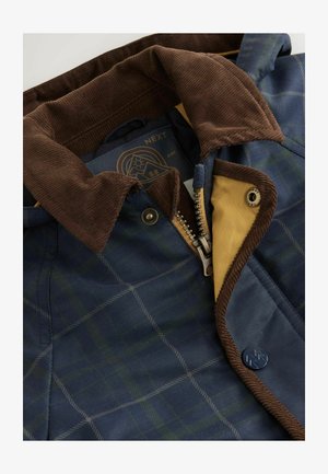 Marineblaues und grünes karierter Mantel mit einem braunen Cordkragen, geliner Futter, Metallreißverschluss und mit markiertem Knopfdetail.