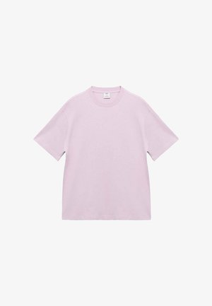 Svetle fialové tričko s krátkým rukávem a volným střihem, s viditelnou etiketou na vnitřní straně límce, na bílém pozadí.