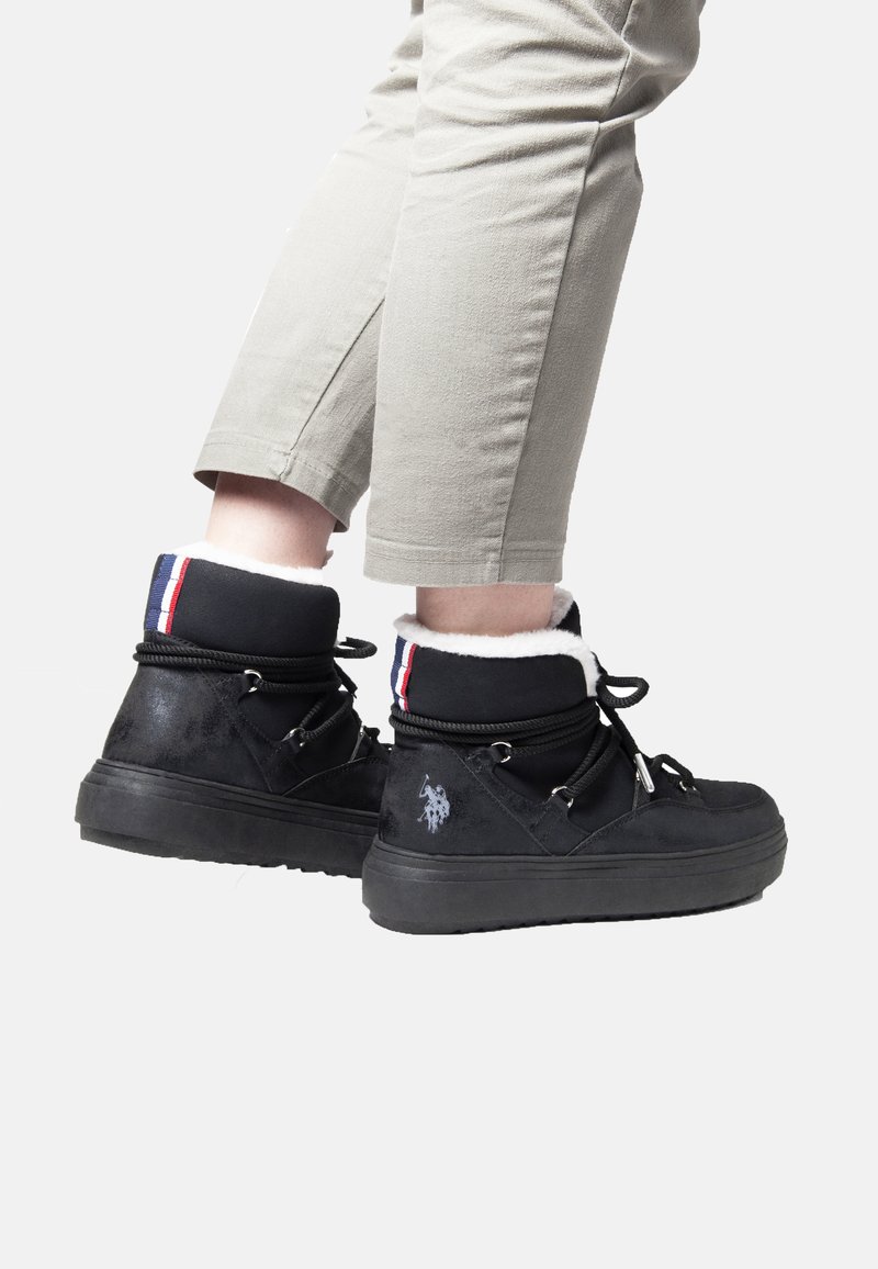 Svarta högstövlar i texturerat tyg, vit pälsfoder och färgglada randiga detaljer. Har framträdande snörning och logotypdetalj.