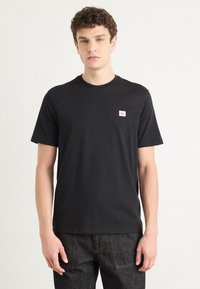 Zwarte katoenen T-shirt met ronde hals, korte mouwen en een klein logo-opdruk op de linkerborst. Simpel en klassiek ontwerp.