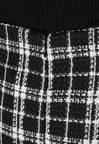 Svart och vit rutigt tyg med en strukturerad yta, med en synlig dragkedja i midjan.