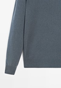Gray knitted sweater with long sleeves, featuring a ribbed hem and cuffs. The fabric appears soft and textured with a subtle sheen.