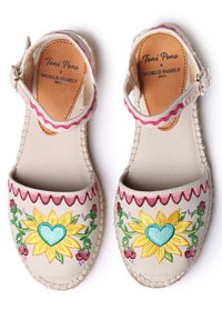 Canvas sandals with embroidered sunflowers and green hearts, cream color, pink scalloped trim, adjustable ankle strap, and woven sole.
