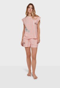 Set di pigiama a righe in pesco e bianco, composto da una maglietta ampia con taschino e pantaloni corti con una grafica giocosa. Tessuto morbido e vestibilità comoda.