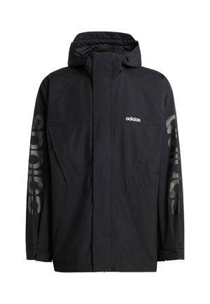 Musta adidas-takki, jossa on korkeakaulus, vedenpitävä materiaali, sivutaskut ja suuri "adidas"-kirjain vasemmassa hihassa.