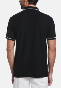 Zwarte poloshirt met een klassieke pasvorm, met witte accenten op de kraag en mouwen. Gemaakt van een zachte katoenen stof.