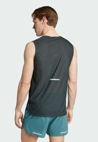 Ärmelloses Sporttanktop in Schwarz mit einem strukturierten Muster. Verfügt über einen reflektierenden Akzent und eine lockere Passform, kombiniert mit türkisfarbenen Shorts.