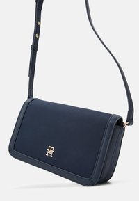 Bolso cruzado de color navy con tejido texturizado, acentos de hardware dorado y cierre de solapa seguro. Correa ajustable para un uso versátil.