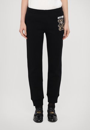 Black sweatpants with a relaxed fit, featuring an embroidered bear graphic and brand logo on the left pocket. Ribbed cuffs complete the design.