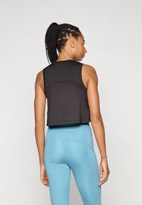 Black cropped tank top with a round neckline and sleeveless design, paired with light blue high-waisted leggings, smooth texture, minimal seams.