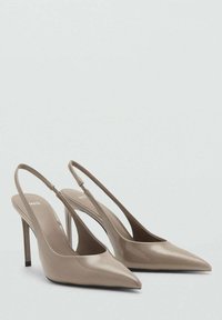 Beige patent leather slingback heels with pointed toes, 10 cm stiletto heels, and minimalistic design featuring a thin ankle strap.