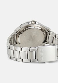 Silver stainless steel watch with a round case, link bracelet, and engraved back. Features a polished finish and a fold-over clasp.