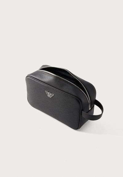 Μαύρο συνθετικό νεσεσέρ με ορθογώνιο σχήμα, ασημένιες λεπτομέρειες φερμουάρ και λογότυπο μπροστά. Διαθέτει πλευρική λαβή για εύκολη μεταφορά.