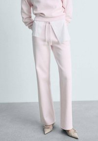 Rosa bomullsmixbyxor med en avslappnad passform, med en vit lagerkant och dragsko i midjan; matchas med spetsiga beige skor.