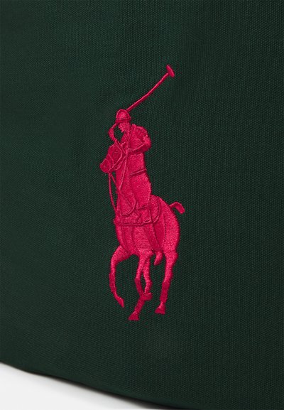 Green fabric bag featuring prominent pink embroidered polo player logo. The texture is smooth, with a structured design and no visible hardware.