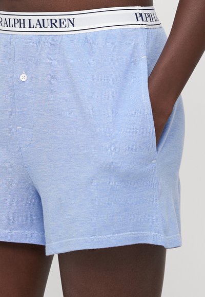 Világoskék pamut rövidnadrág, texturált felszínnel, oldalsó zsebekkel, elülső gombbal és rugalmas derékrésszel, melyet "Ralph Lauren" felirattal láttak el.