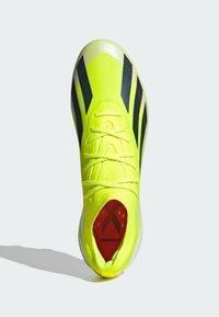 Neon gul atletikskor med en strukturerad ovandel, svarta diagonala ränder och en röd sulan märkt "CRAZYFAST". Vit yttersula.