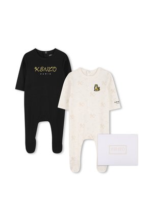 Deux grenouillères pour bébé, une noire avec "Kenzo Paris" en jaune, une blanche avec de petits imprimés et un petit écusson tigre, à côté d'une boîte Kenzo blanche.
