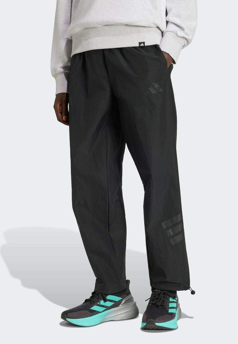 Pantalon de sport noir léger avec une finition texturée. Comprend un cordon de serrage à l'ourlet et des accents de logo à trois bandes sur les jambes.