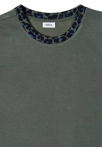 Olive green shirt with black and blue leopard print trim around round neckline and white label reading "CECIL" inside collar.