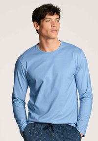Lichtblauwe shirt met lange mouwen, gemaakt van een zachte stof, gecombineerd met marineblauwe geblokte broek met strepen en stippen, casual pasvorm.
