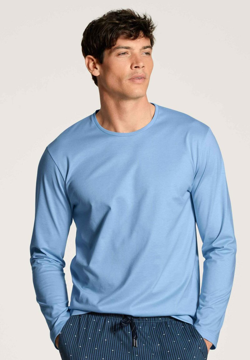 Lichtblauwe shirt met lange mouwen, gemaakt van een zachte stof, gecombineerd met marineblauwe geblokte broek met strepen en stippen, casual pasvorm.
