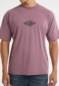 Paarse katoenen t-shirt met korte mouwen, met een zwart grafisch logo dat "ORIGINALS" in het midden afdrukt. Casual pasvorm, eenvoudig ontwerp.